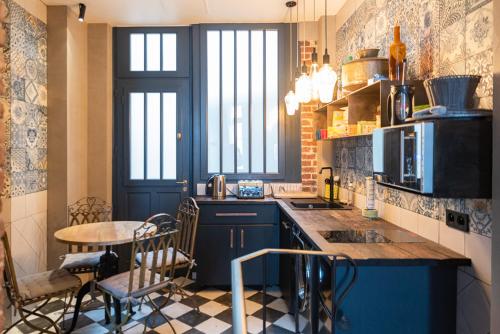 eine Küche mit blauen Schränken und einem Tisch mit Stühlen in der Unterkunft Superbe Hammam à Paris Montparnasse in Paris