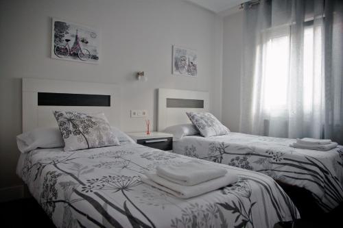 1 dormitorio con 2 camas y ventana en Zubia Home Portugalete - Impecable- 3 min metro Bilbao en Portugalete