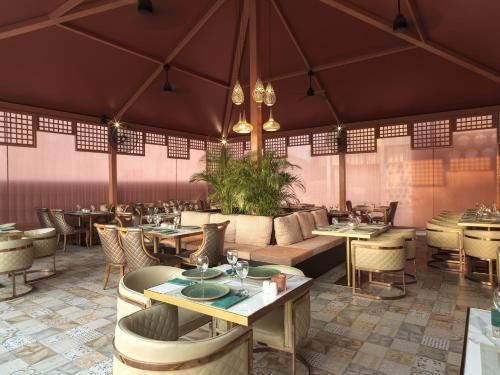 a restaurant with tables and couches and chairs at Leonardo Laura Beach & Splash Resort in Paphos City