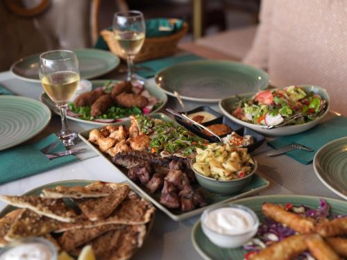 a table with plates of food and glasses of wine at Leonardo Laura Beach & Splash Resort in Paphos City