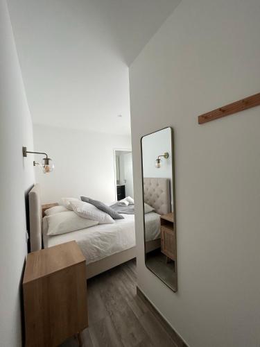 une chambre blanche avec un lit et un miroir dans l'établissement La Forêt d'Armotte villa 16, à Saint-Augustin