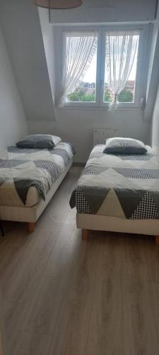 deux lits dans une chambre avec deux fenêtres dans l'établissement Appartement lumineux et fonctionnel en bord de mer, à Villers-sur-Mer