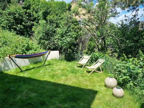 a yard with two chairs and a hammock in the grass at Le toit de Chardonne - Entre Alpes et lac Léman in Chardonne