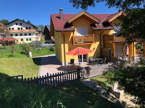 a yellow house with a fence and an umbrella at KWO-villa 46-OK The Comfort Zone in Arnoldstein