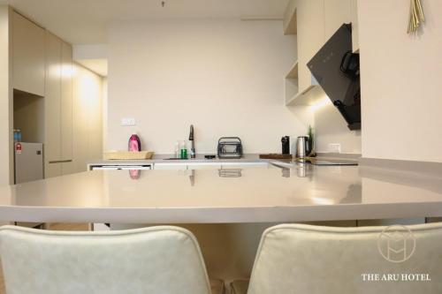 a kitchen with a white counter and two chairs at The Aru Hotel at Aru Suites in Kota Kinabalu