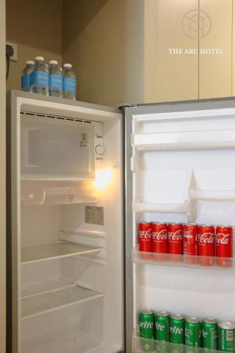 an open refrigerator with soda cans inside of it at The Aru Hotel at Aru Suites in Kota Kinabalu