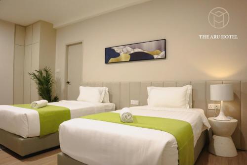 a hotel room with two beds with green and white sheets at The Aru Hotel at Aru Suites in Kota Kinabalu