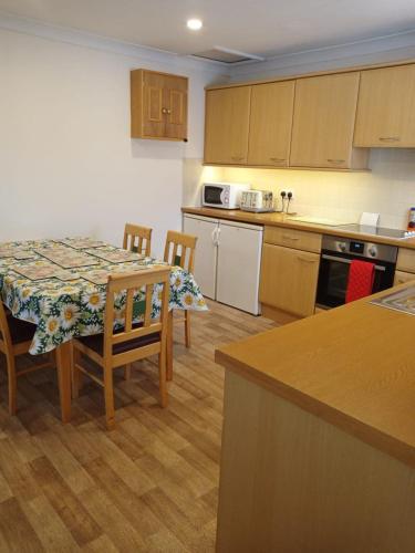 a kitchen with a table and chairs and a kitchen with a table and a kitchen at Glen Dhoo Country Cottages - The Apartment in Onchan