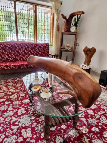 ein Wohnzimmer mit einem Couchtisch aus Glas mit einer hölzernen Hand in der Unterkunft White Butterfly - A Countryside Homestay in Thiruvananthapuram