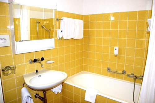 a bathroom with a sink and a bath tub at Hotel Salastrains in St. Moritz