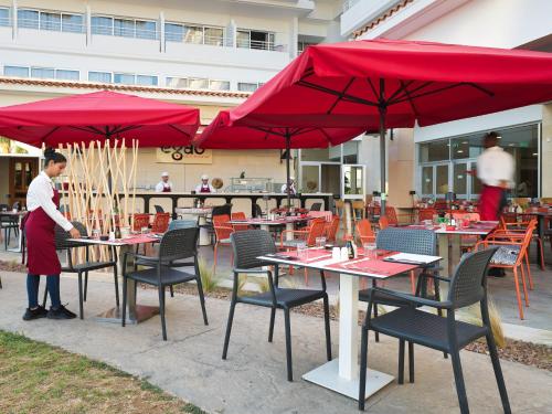 a person standing at a table with red umbrellas at Leonardo Cypria Bay in Paphos City