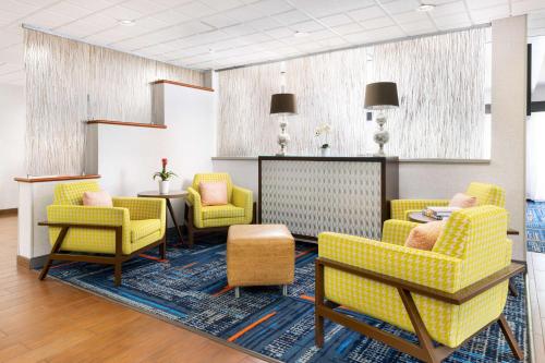a waiting room with yellow chairs and a table at Hampton Inn Naples-Central in Naples