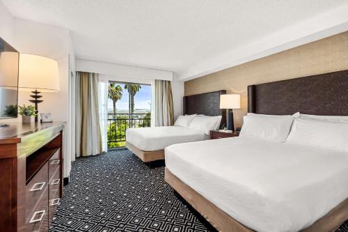 a hotel room with two beds and a balcony at Embassy Suites by Hilton Los Angeles International Airport South in El Segundo