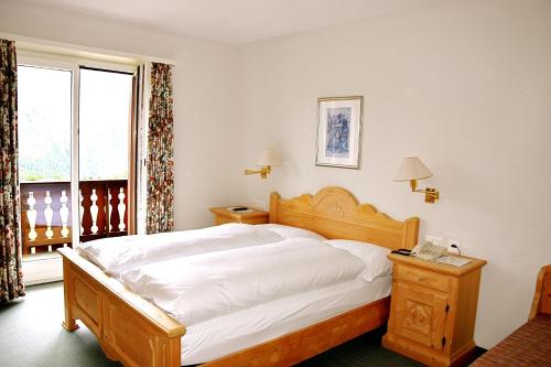 a bedroom with a large white bed with a telephone at Hotel Salastrains in St. Moritz