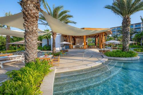 a resort with a swimming pool and palm trees at Conrad Punta de Mita in Punta Mita