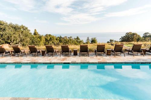a group of chairs sitting next to a swimming pool at Alila Ventana Big Sur, All Inclusive Adults Only in Big Sur