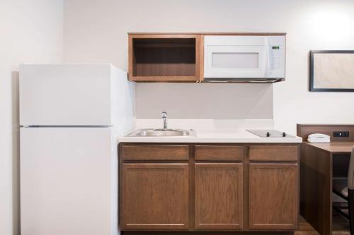 a kitchen with a white refrigerator and a sink at WoodSpring Suites Savannah Pooler in Savannah
