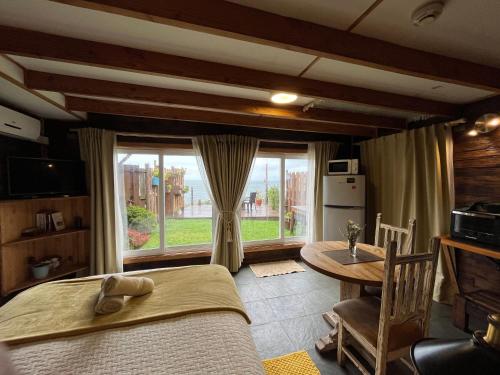 1 dormitorio con cama, mesa y ventana en Cabañas Fischer SpA, en Niebla