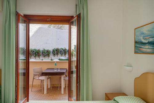 アルゲーロにあるHotel El Balearのテーブルと窓が備わる小さな客室です。