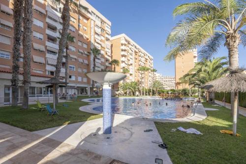 a swimming pool in a resort with palm trees and buildings at Urbanización Bulevar Playa in Benimagrell