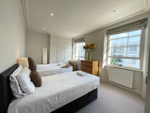 a large bedroom with two beds and a window at Victoria Maisonette Apartment in London