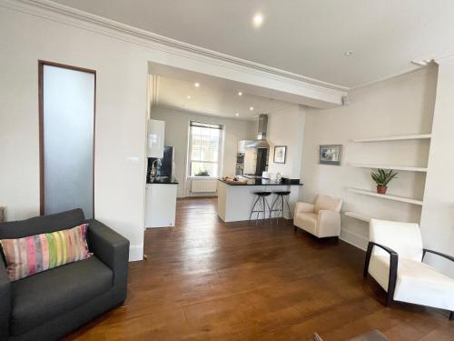 Victoria Maisonette Apartment في لندن: غرفة معيشة ومطبخ مع أريكة وطاولة