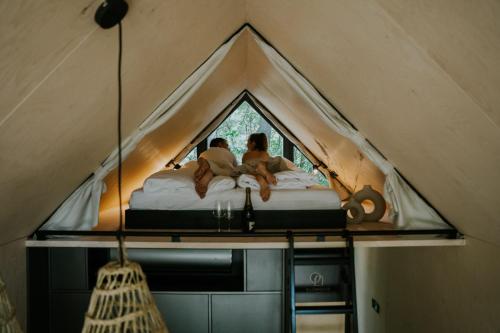 dos personas acostadas en una cama en una tienda en Slowood Cabins, en Balatonszepezd