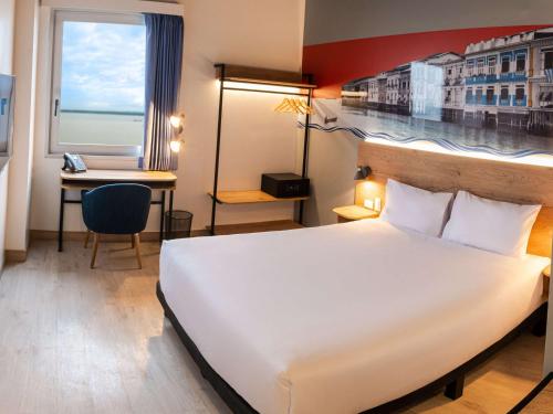 ein Hotelzimmer mit einem großen Bett und einem Schreibtisch in der Unterkunft Ibis Styles El Malecon Guayaquil in Guayaquil