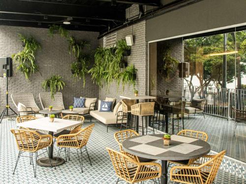 a patio with tables and chairs and a brick wall at Ibis Styles El Malecon Guayaquil in Guayaquil