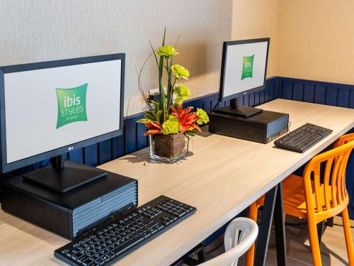 a desk with two computer monitors on top of it at Ibis Styles El Malecon Guayaquil in Guayaquil