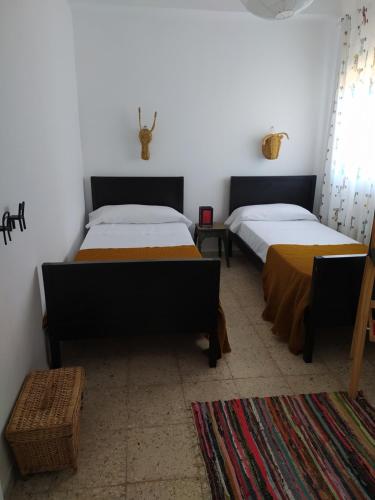 a bedroom with two beds and a table and a rug at La Zagala in Badajoz