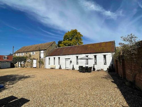 an old white barn with a rusty roof at The Old Hay Barn - Games Room, Gym, Sleeps 8 in Godmanchester