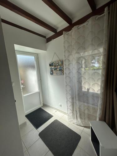 a bathroom with a shower curtain and a window at La Maisonnette in Les Pieux