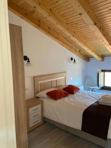 a bedroom with a bed with red pillows on it at Apartamentos Rurales La Plaza 2 in Duruelo de la Sierra