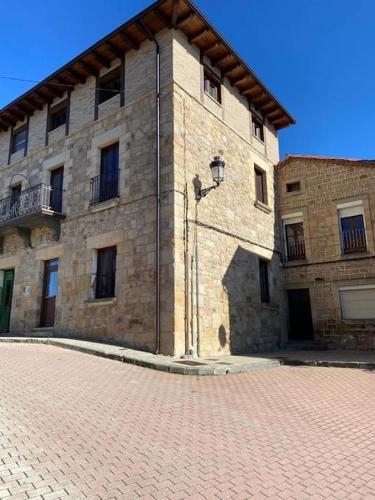 un grand bâtiment en briques avec un trottoir en briques devant lui dans l'établissement Apartamentos Rurales La Plaza 2, à Duruelo de la Sierra