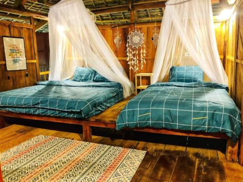 a bedroom with two beds with curtains and a rug at Pu Luong Homestay & Tours in Hương Bá Thước