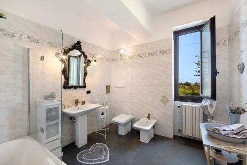 Baño blanco con lavabo, bañera y espejo en Beautiful Tagliolo, en Tagliolo Monferrato