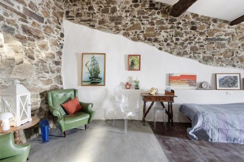 a bedroom with a stone wall and a bed and a chair at Schiara in Campiglia