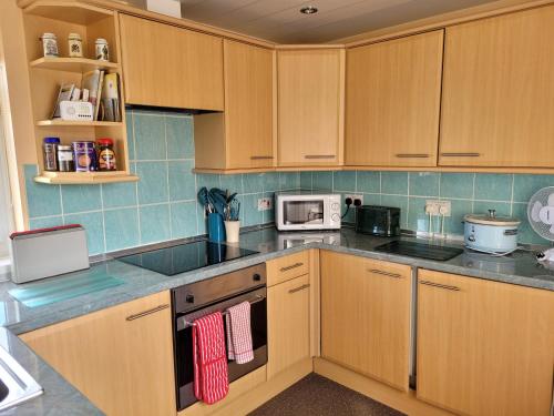 a kitchen with wooden cabinets and a stove top oven at No 27 Guisborough - 1 bed apartment in Guisborough
