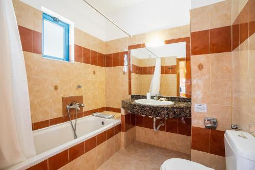 a bathroom with a tub and a sink and a toilet at Livadia Beach Tilos Apartment in Livadia