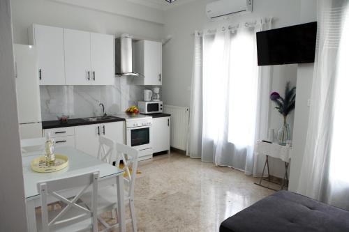 a kitchen with white cabinets and a table and chairs at Didis Place Nafplio in Nafplio