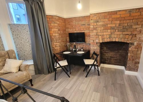 a living room with a table and a brick wall at Sunnyside Studio Apartment in Llandrindod Wells