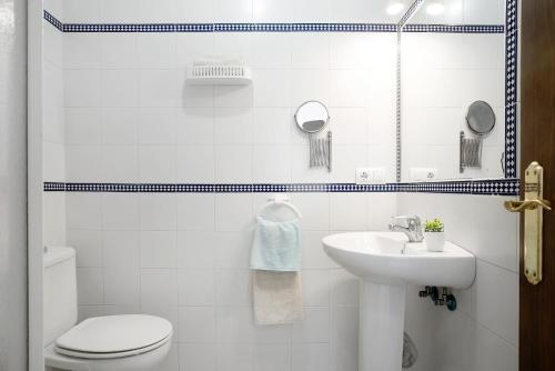 een witte badkamer met een toilet en een wastafel bij Casa María in Conil de la Frontera