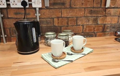 dos tazas de café sentadas encima de un mostrador en Sunnyside Studio Apartment en Llandrindod Wells