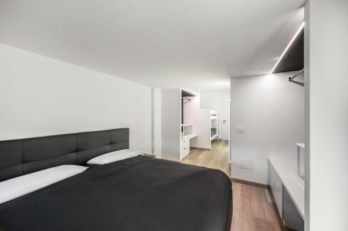 a bedroom with a black bed and white walls at Appartamento Mazzin in Mazzin