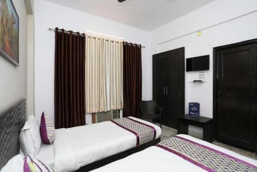 a hotel room with two beds and a desk at Hotel Ace Plaza in Udaipur