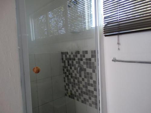 een badkamer met een douche en een glazen deur bij Lalapanzi, A place to rest in Bloemfontein