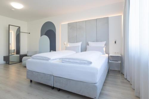 a bedroom with a large white bed with a large headboard at zzzpace Smart-Hotel Bielefeld Zentrum in Bielefeld