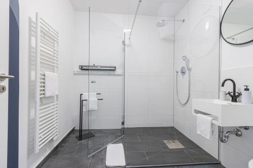 a white bathroom with a shower and a sink at zzzpace Smart-Hotel Bielefeld Zentrum in Bielefeld