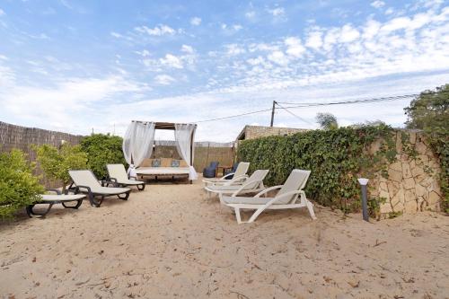 a group of lounge chairs and a bed on a beach at Casa Verdelho in Palmela